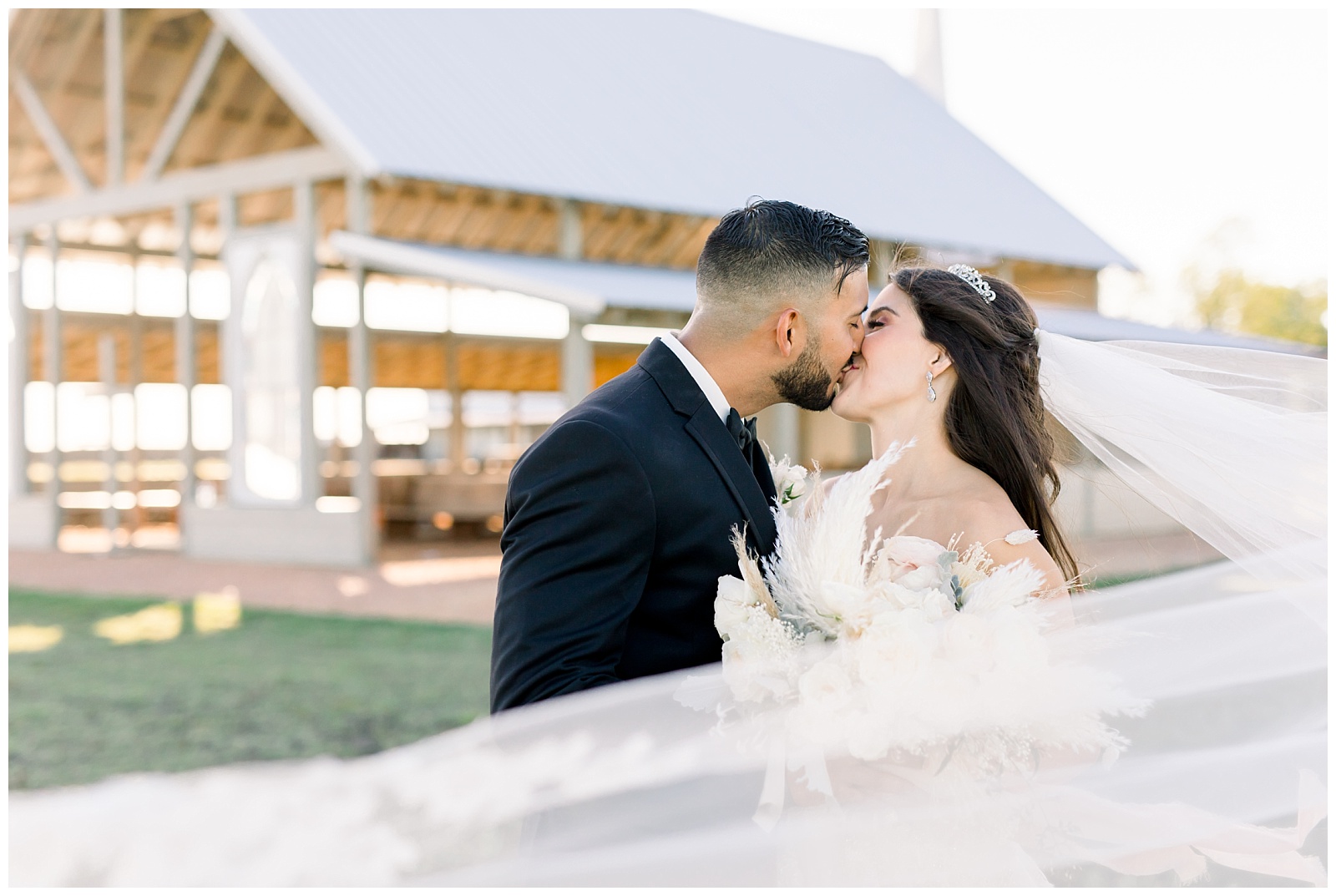Bride and groom kiss while her veil sweeps in the wind around them at The Allen Farmhaus Wedding, TX by San Antonio-Maui-Destination Wedding Photographer | Monica Roberts Photography | www.monicaroberts.com