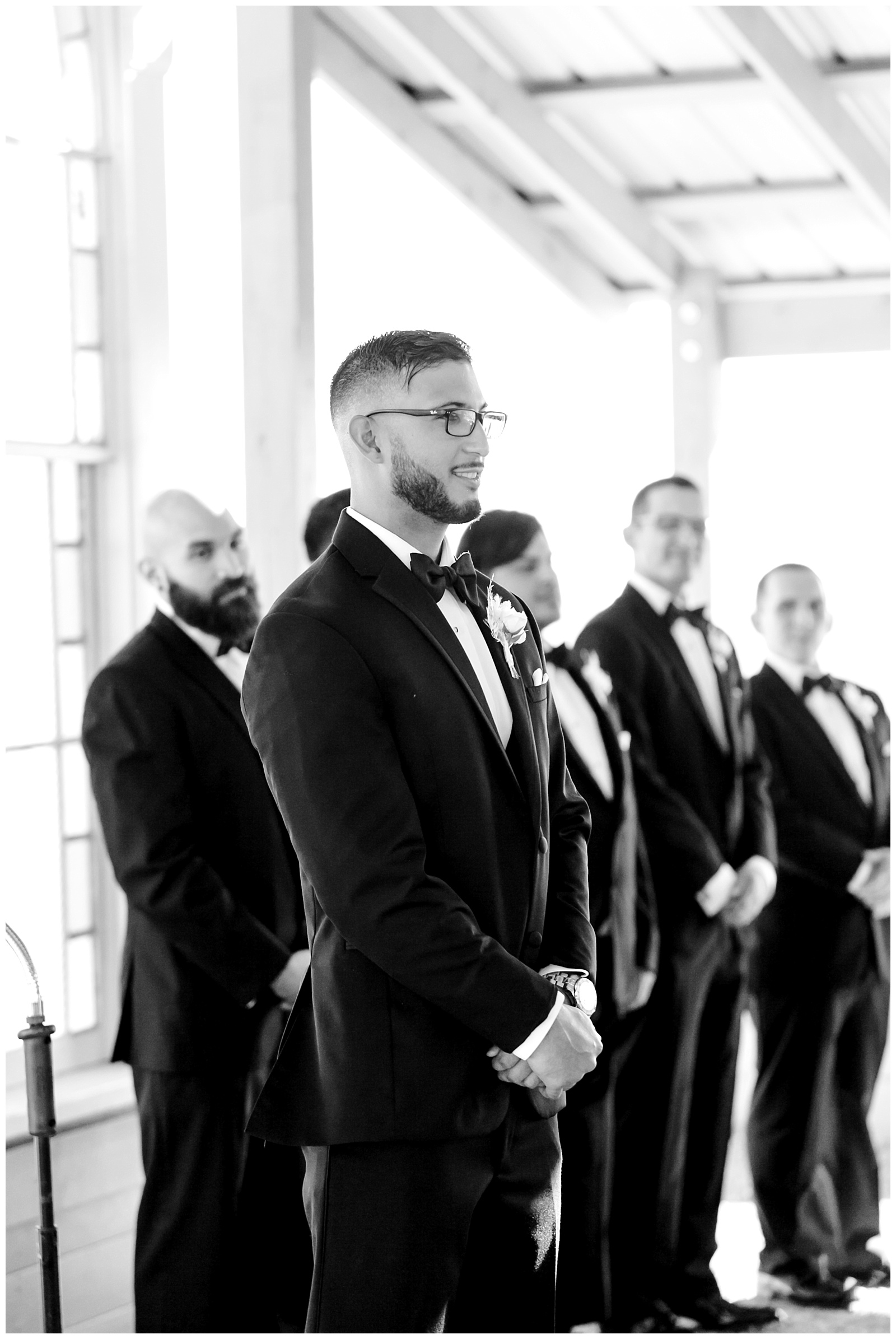 Black and white close up of groom looking down the aisle as his bride walks up at The Allen Farmhaus Wedding, TX by San Antonio-Maui-Destination Wedding Photographer | Monica Roberts Photography | www.monicaroberts.com