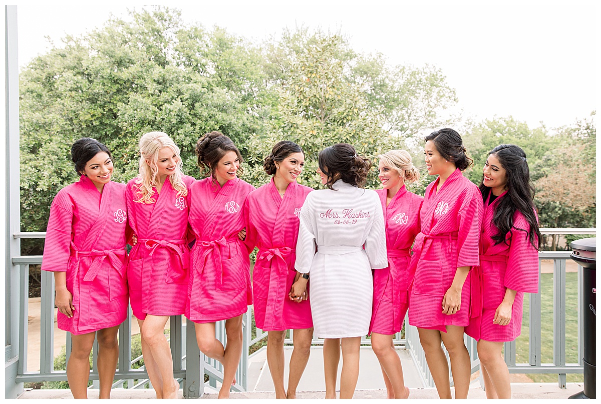 Bridesmaids standing with bride in robes while bride shows off labeling on the back of her robe at Hyatt Regency Hill Country Resort Wedding in San Antonio, TX | San Antonio Wedding photographer| Destination Wedding Photographer| Monica Roberts Photography | monicaroberts.com