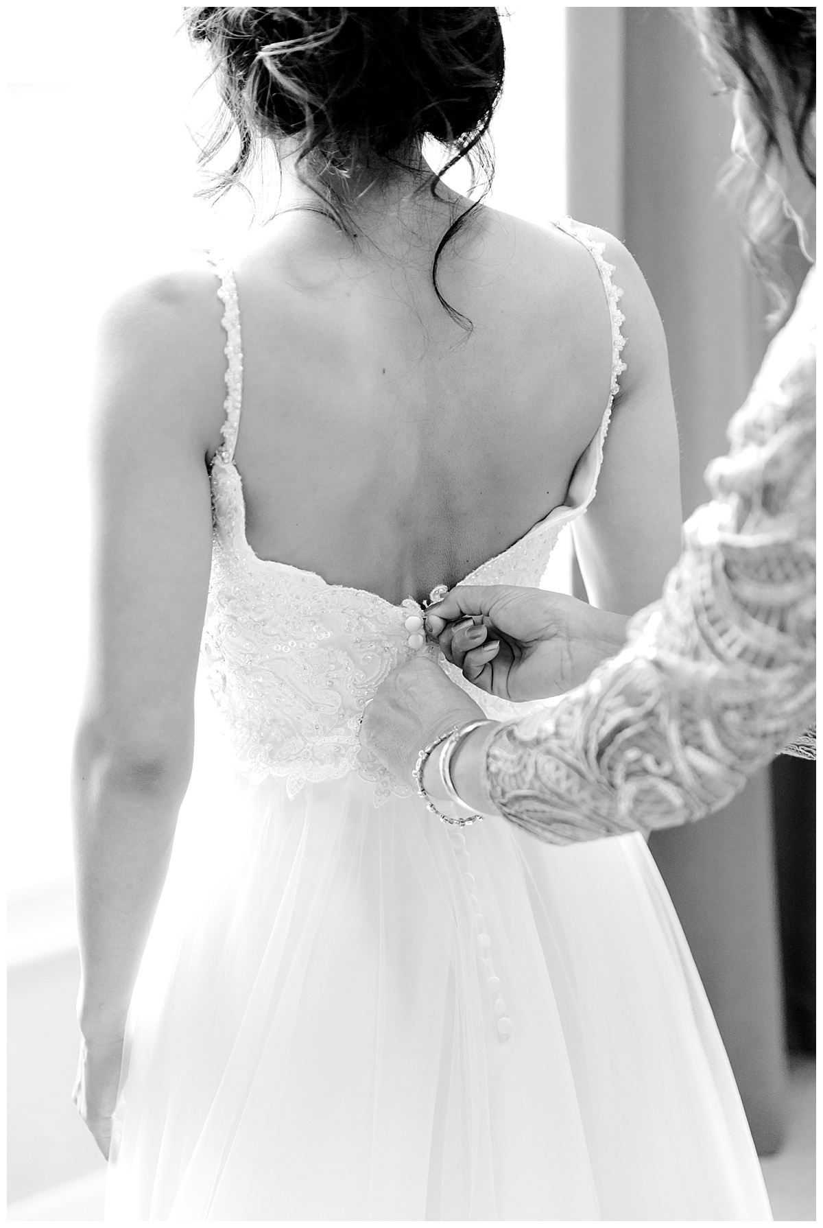 Black and white shot of back of bride's dress while mother zips it up at Hyatt Regency Hill Country Resort Wedding in San Antonio, TX | San Antonio Wedding photographer| Destination Wedding Photographer| Monica Roberts Photography | monicaroberts.com