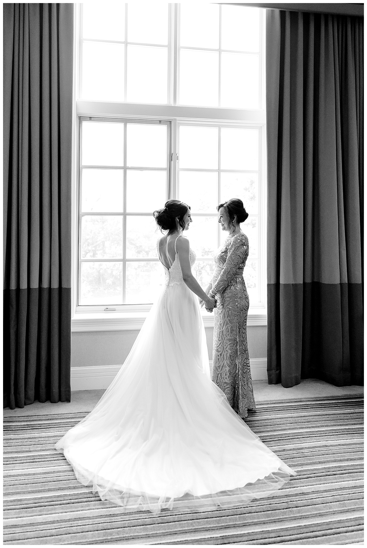 Black and white photo of bride holding hands with her mother in front of bright window with train flowing out behind her at Hyatt Regency Hill Country Resort Wedding in San Antonio, TX | San Antonio Wedding photographer| Destination Wedding Photographer| Monica Roberts Photography | monicaroberts.com