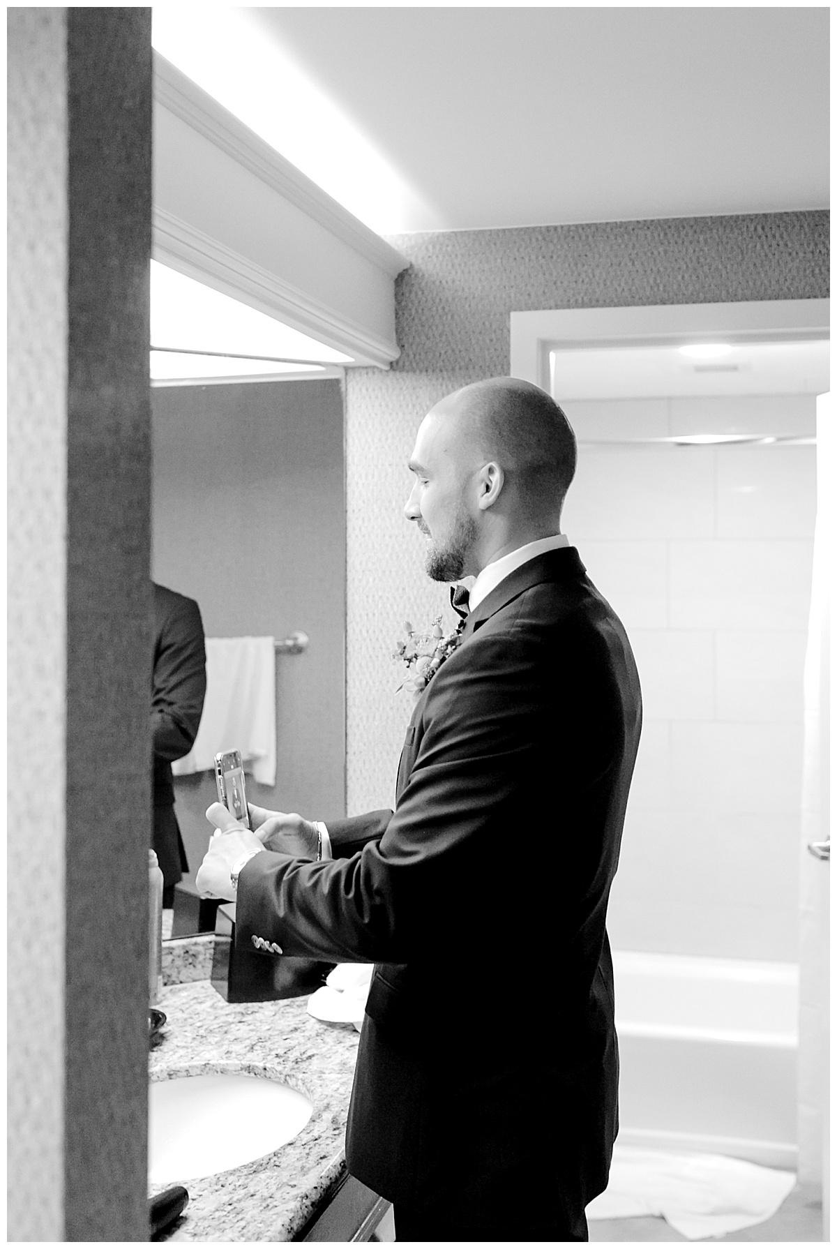 Black and white shot of groom standing in bathroom and taking a photo of himself at Hyatt Regency Hill Country Resort Wedding in San Antonio, TX | San Antonio Wedding photographer| Destination Wedding Photographer| Monica Roberts Photography | monicaroberts.com