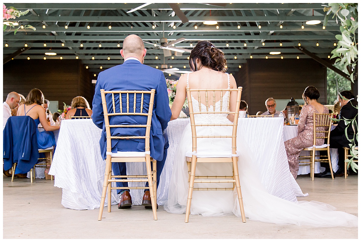View from behind as bride and groom sit together at their table at reception at Hyatt Regency Hill Country Resort Wedding in San Antonio, TX | San Antonio Wedding photographer| Destination Wedding Photographer| Monica Roberts Photography | monicaroberts.com
