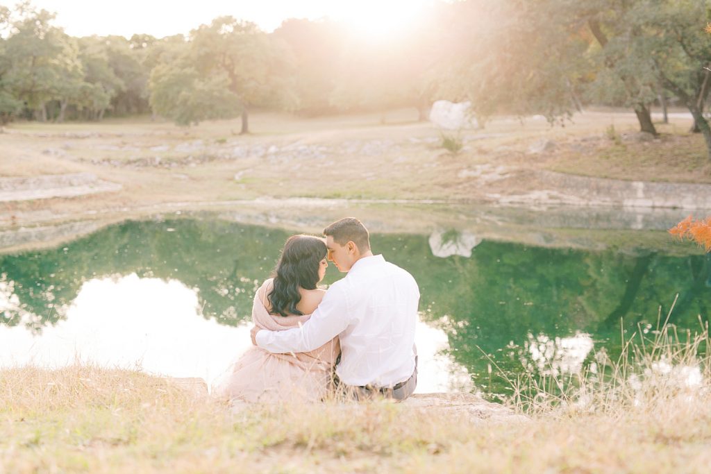 couple sitting in front of a pond thats backlit with golden sun for a Romantic Engagement session at Kendall Plantation with Monica Roberts Photography www.monicaroberts.com