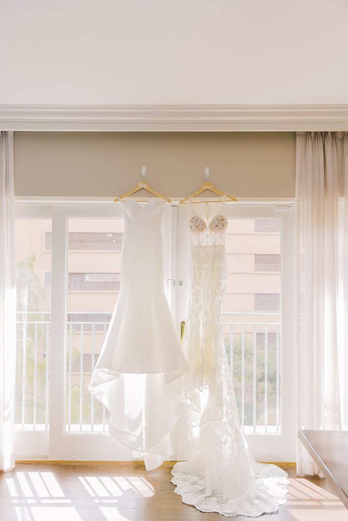 2 wedding dresses hanging in a window for a wedding at the Jack Guenther Pavilion at the Briscoe in San Antonio with Monica Roberts Photography - https://monicaroberts.com/