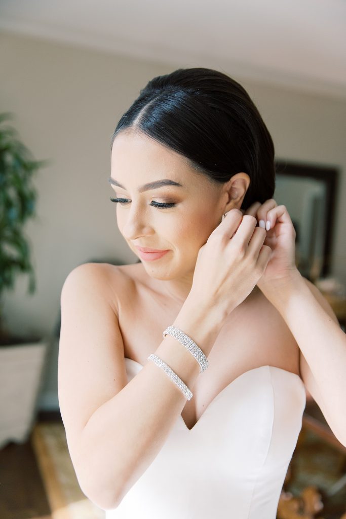 classic photo of bride putting earrings on for a wedding at the Jack Guenther Pavilion at the Briscoe in San Antonio with Monica Roberts Photography - https://monicaroberts.com/