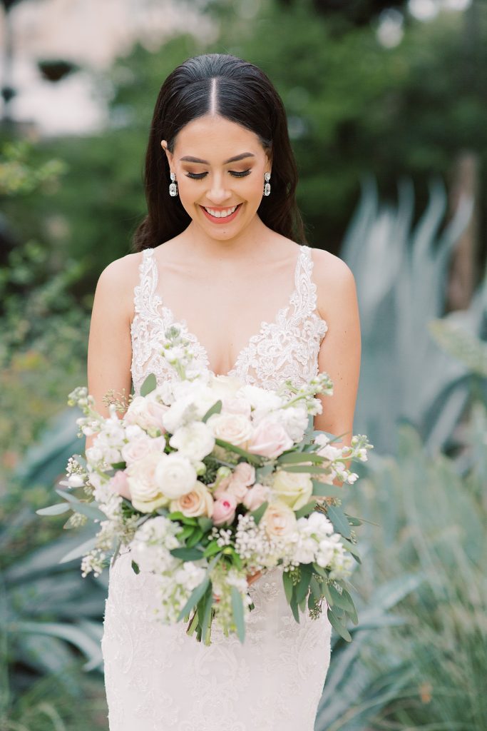 bride looking at her flowers for a wedding at the Jack Guenther Pavilion at the Briscoe in San Antonio with Monica Roberts Photography - https://monicaroberts.com/