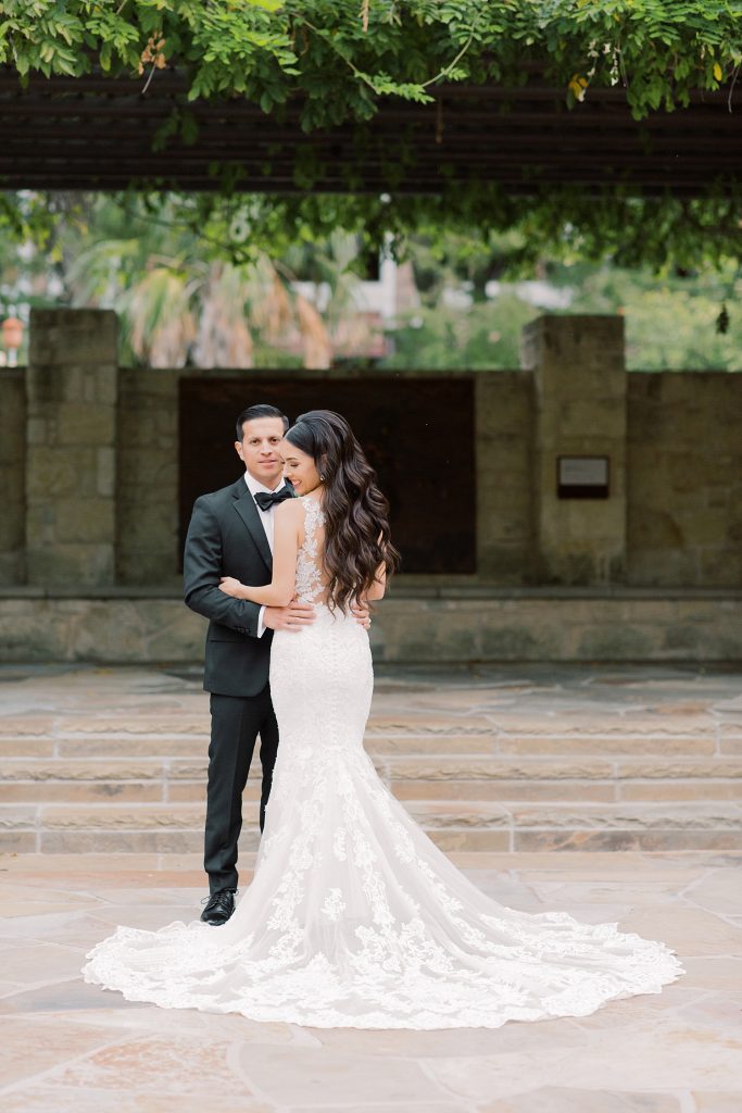 groom looking over his brides shoulder smiling for a wedding at the Jack Guenther Pavilion at the Briscoe in San Antonio with Monica Roberts Photography - https://monicaroberts.com/