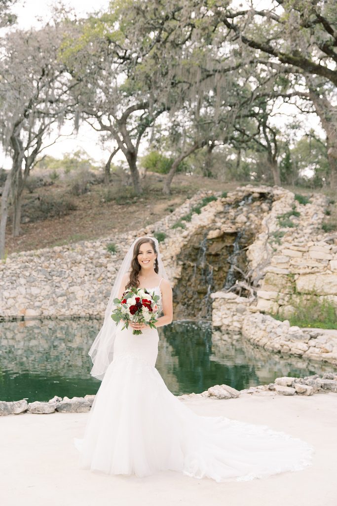 bride walking and smiling with a waterfall behind her for her Bridal Portraits at Hayes Hollow in Spring Branch, TX with Monica Roberts Photography www.monicaroberts.com