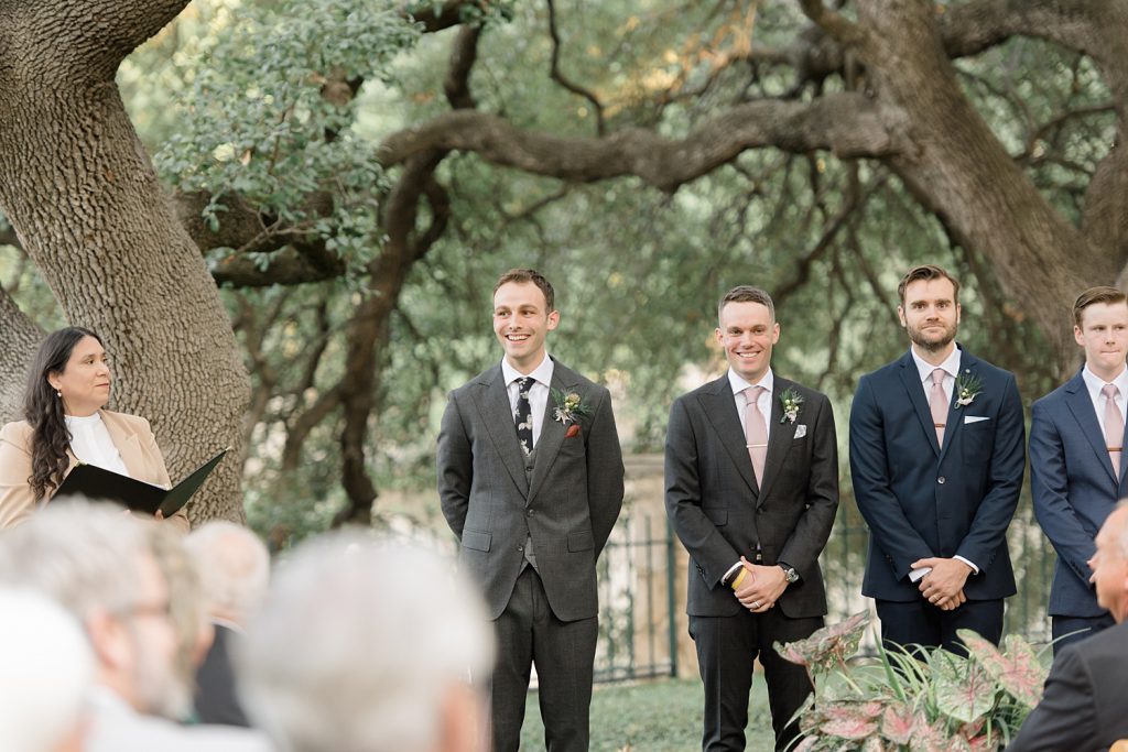 groom smiling as his bride walks down the aisle for a gorgeous outdoor garden wedding at The Guenther House in San Antonio, TX | Monica Roberts Photography | www.monicaroberts.com