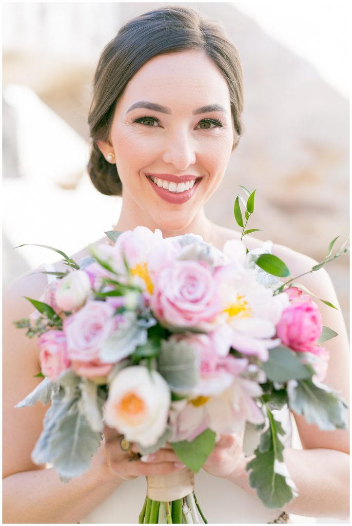 bride smiling at camera while holding her florals close to her face for her bridals in Richmond, Virginia