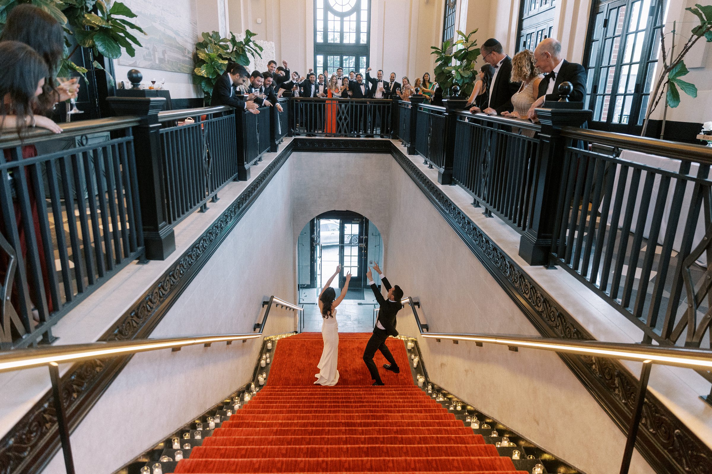 A joyful moment as guests celebrate the couple with traditional Jewish dancing, including the hora, lifting them into the air on chairs